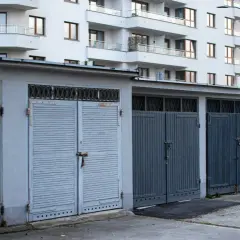 Rząd garaży wolnostojących zamykanych na kłódki, na tle nowoczesnego bloku mieszkalnego. Zastanawiasz się, ile kosztuje garaż wolnostojący?