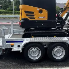 Żółta minikoparka SY18C na przyczepie. Zastanawiasz się, ile waży minikoparka? Ta jest gotowa do transportu.