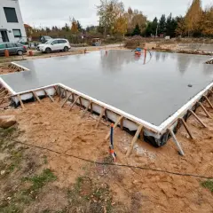 Świeżo wylana płyta betonowa na budowie. Czy tańsze płyta czy fundament? Widać zbrojenie i szalunki.