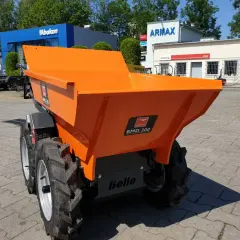 Pomarańczowe, małe wozidła budowlane stoją na placu przed budynkami.