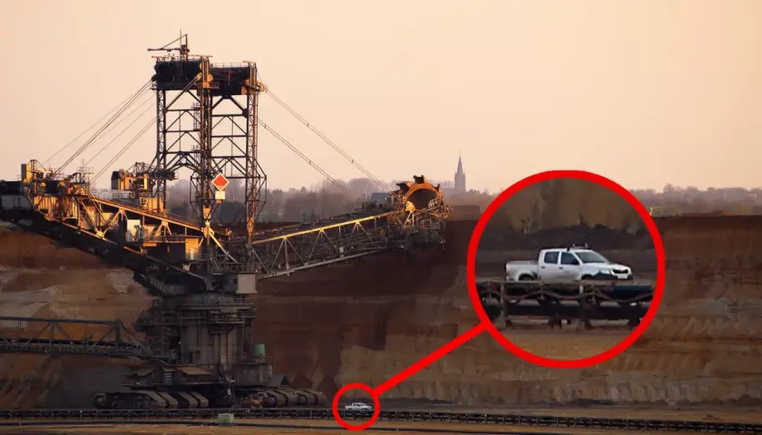 Gigantyczna koparka, największa koparka na świecie, w kopalni odkrywkowej. W powiększeniu widać mały biały pickup.