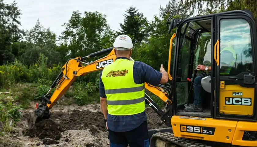 Instruktor z Akademii Operatora pokazuje, jak obsługiwać koparkę podczas kursu na fadrome.