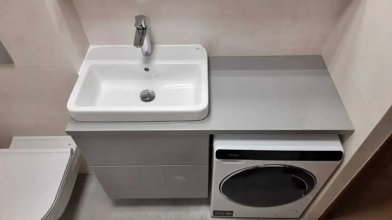 Nowoczesna, mała łazienka w bloku z pralką pod blatem i umywalką. Zastanawiasz się, ile kosztuje remont małej łazienki w bloku?
