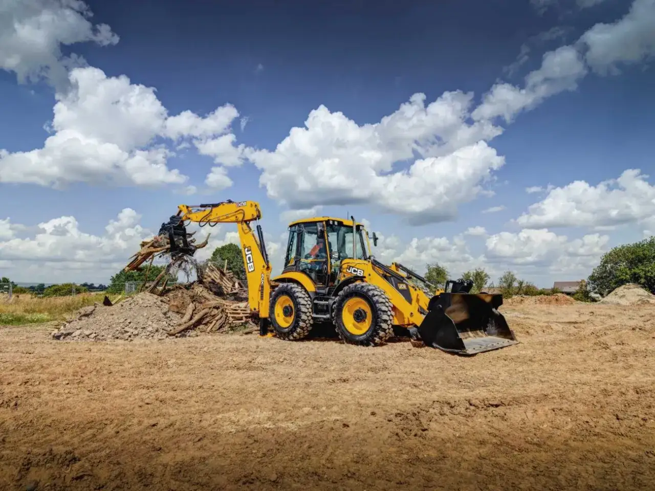 Koparka JCB pracuje na budowie, usuwając gruz. Sprawdź JCB Polska cennik dla swojej inwestycji.